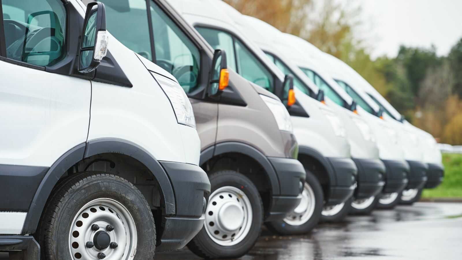 Bouwbedrijf bestelwagen met aanhangwagen en mini-graafmachine die naar werf rijden